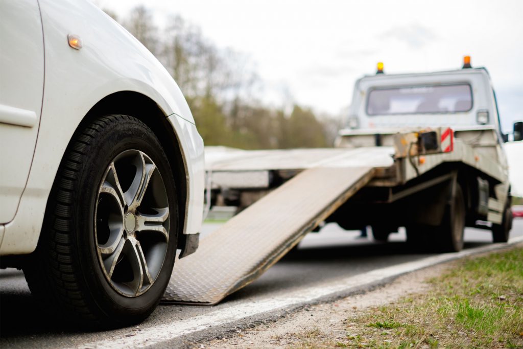 Loading broken car on a tow truck on a roadside